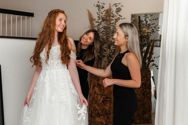 Brautberatung bei Clebeo Love Braut, die bei der Anprobe von Mitarbeitern beraten wird